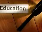 Szkło powiększające na białym tle na podłożu drewnianym, napis "education" na kartce