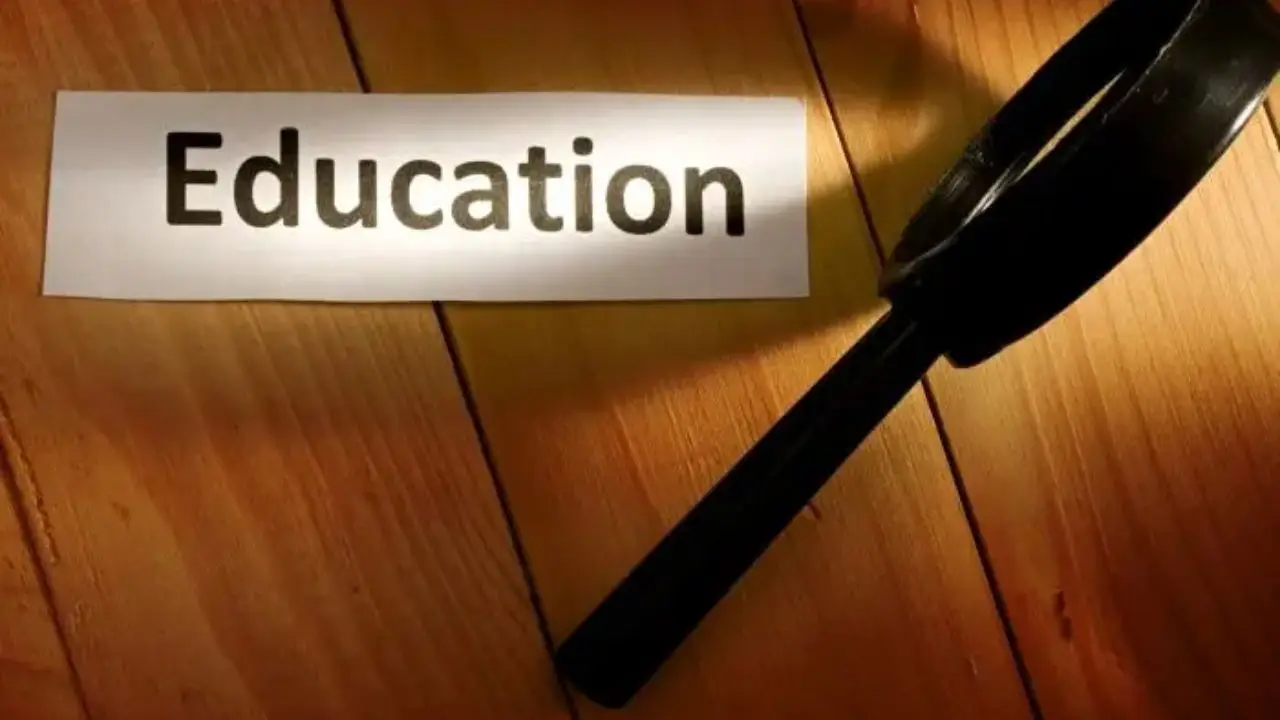 Szkło powiększające na białym tle na podłożu drewnianym, napis "education" na kartce