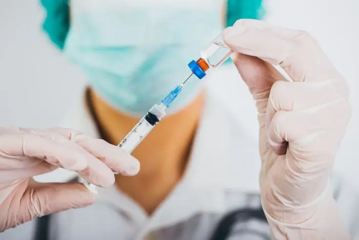 Osoba w maseczce trzymająca strzykawkę ze szczepionką w dłoni