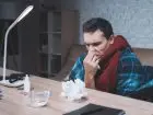 Chory meżczyzna przy biurku pod kocem