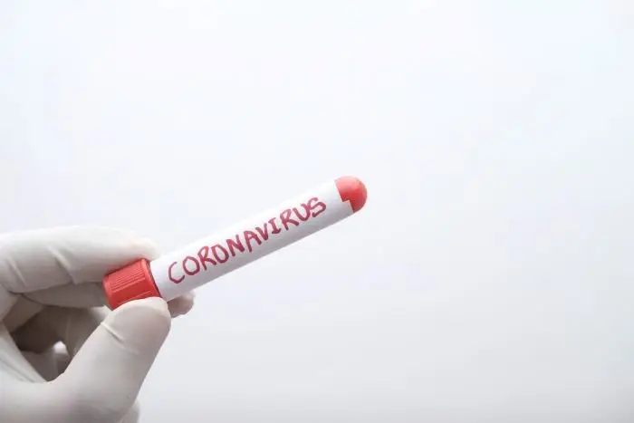 Fiolka z napsiem coronavirus trzymana w dłoni w rękawiczce