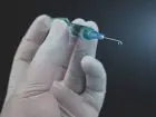 Strzykawka ze szczepionką trzymana w dłoni w rękawiczce