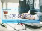 Mężczyzna poszukujący pracy w Internecie na tle napisu job search