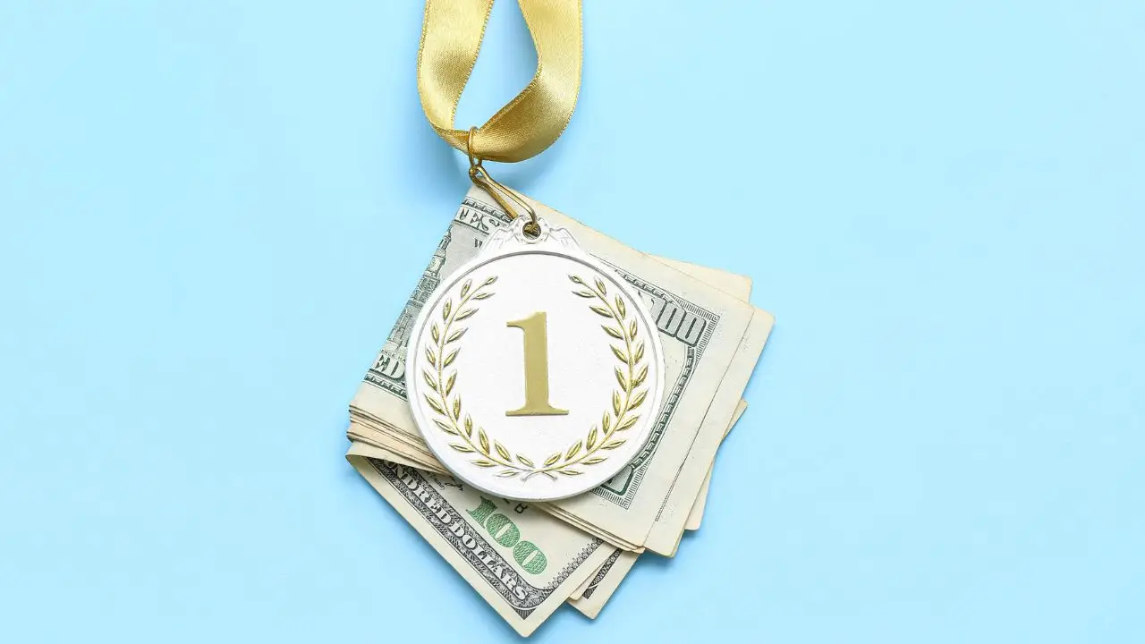 Podatek od nagrody w pracy - medal położony na banknotach na niebieskim tle