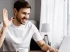 Kontrola pracy zdalnej - mężczyzna uśmiechnięty przed komputerem w domu