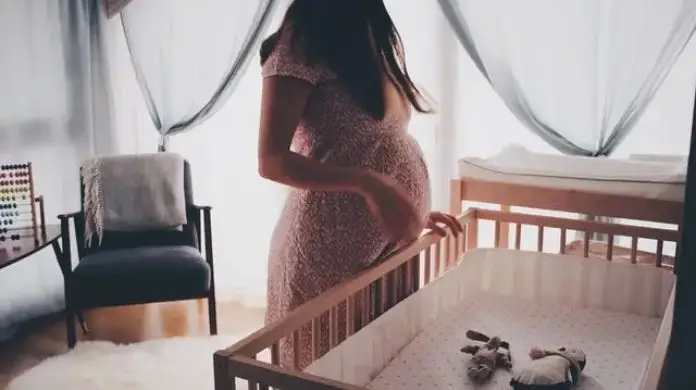 L4 w ciąży - kobieta stojąca przy łóżeczku dziecięcym