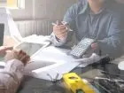 Rzeczoznawca majatkowy - mężczyzna przy biurku, dokonujący obliczeń przy użyciu kalkulatora