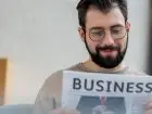 Dwa rodzaje działalności jedna firma - gazeta business trzymana w dłoniach przez mężczyznę
