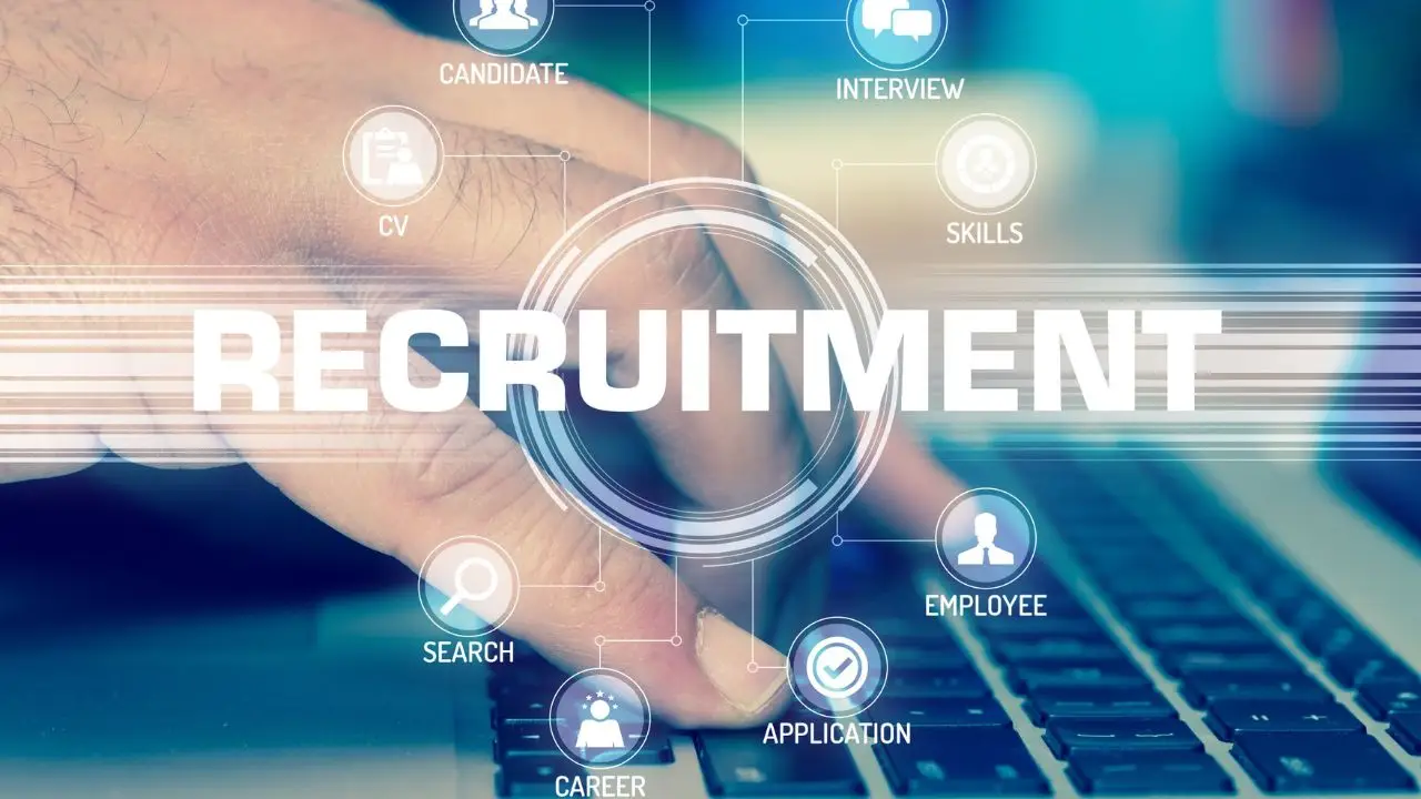 Ile zarabia rekruter IT - napis recrutiment i zbliżenie na dłoń osoby piszącej na klawiaturze laptopa