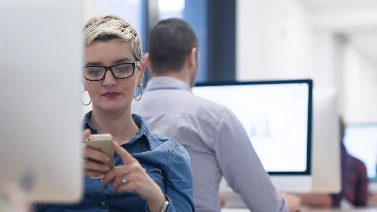 Pracownicy w biurze, zbliżenie na kobietę używającą telefonu