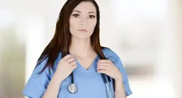 Jak zostać pielegnairką - kobieta w fartuchu ze stetoskopem na szyi
