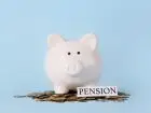 Napis pension, skarbonka świnka i monety na niebieskim tle