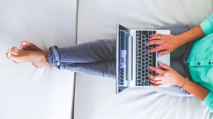 Praca w domu - kobieta z laptopem na nogach