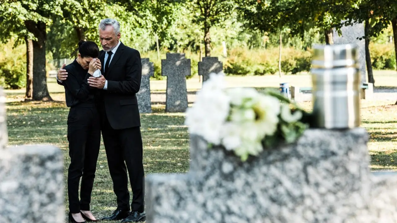 Urlop okolicznościowy: śmierć matki - dwie osoby przy grobie na cmentarzu