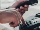 Zbliżenie na dłoń podczas wybeirania numeru na telefonie stacjonarnym