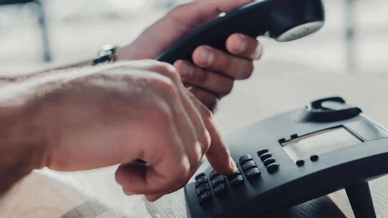 Zbliżenie na dłoń podczas wybeirania numeru na telefonie stacjonarnym