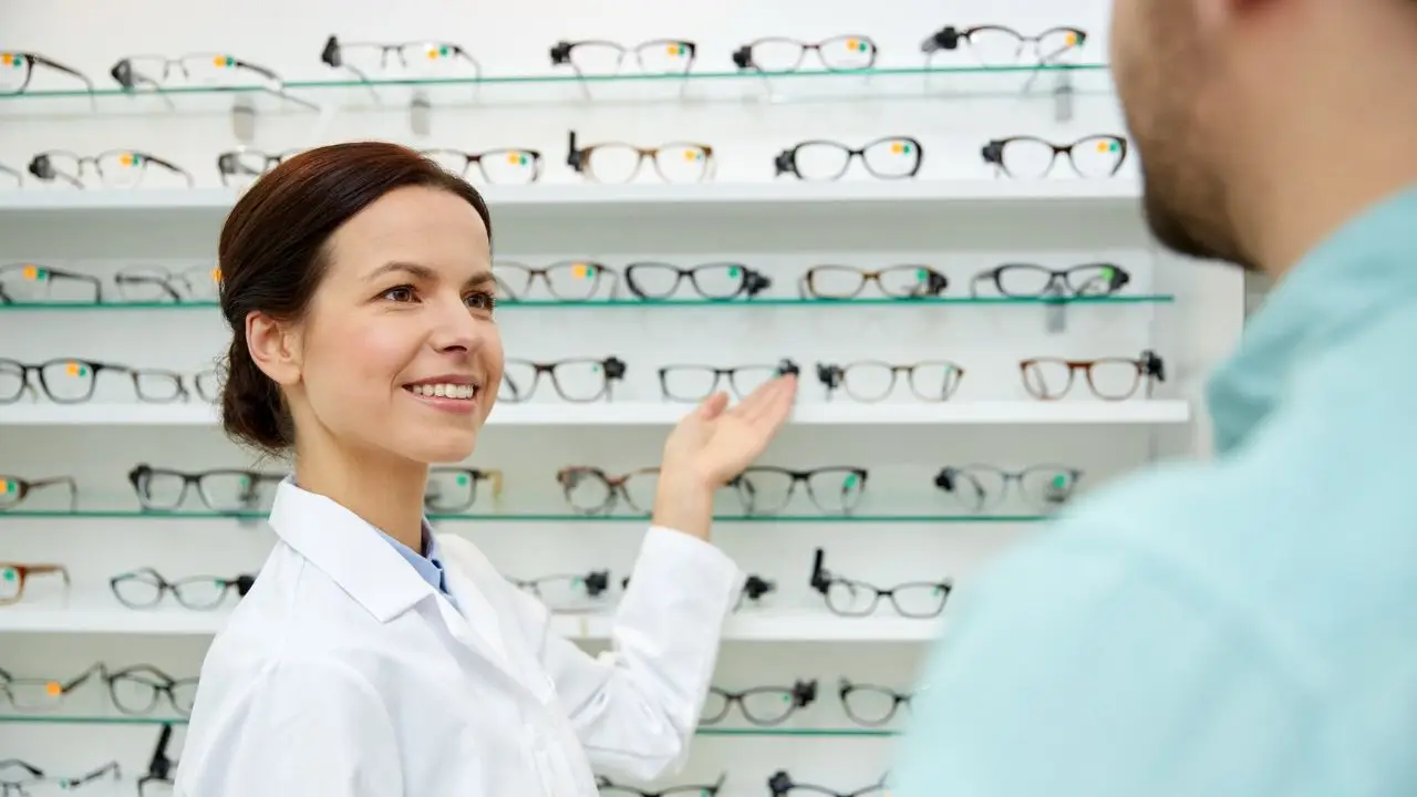 Kobieta optyk pokazuje klientowi okulary