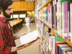 Praca w bibliotece - bibliotekarz przeglądający książki w bibliotece