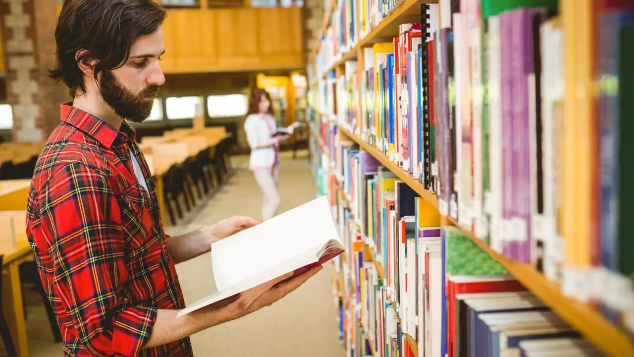 Praca w bibliotece - bibliotekarz przeglądający książki w bibliotece