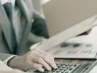 Księgowa CV - zbliżenie na dłoń księgowej korzystającej z kalkulatora i analizującej dokumenty