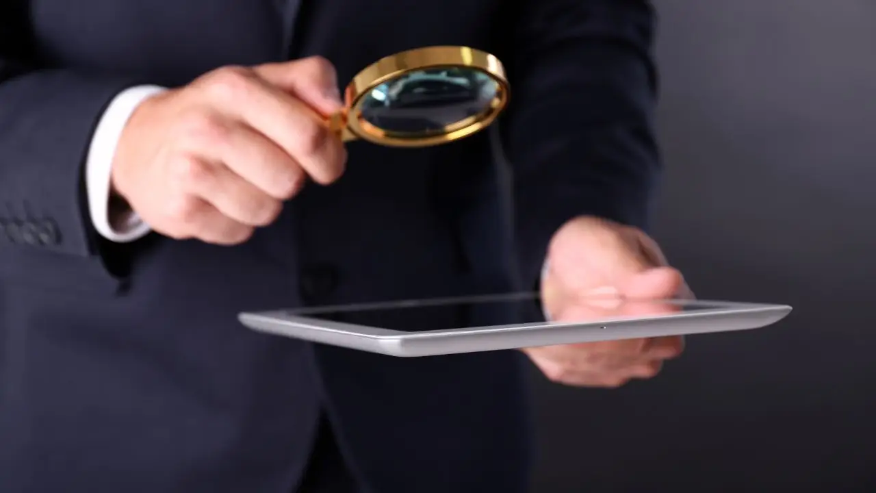 Audytor wewnętrzny - mężczyzna przyglądający się przez lupę ekranowi tabletu