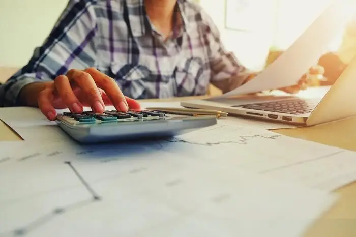 Kapitał obrotowy - kobieta oblicza rachunki na kalkulatorze siedząc przy biurku