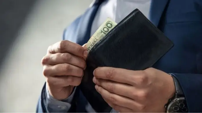 Przeciętne wynagrodzenie - mężczyzna wyciągający banknot z portfela