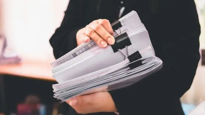 Referent - kobieta ze stosem dokumentów w dłoniach