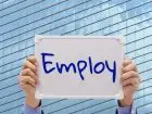 Wakat - napis employ trzymany w dłoniach na tle biurowca