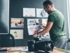 Ile zarabia fotograf - fotograf rozwieszający zdjęcia na ścianie