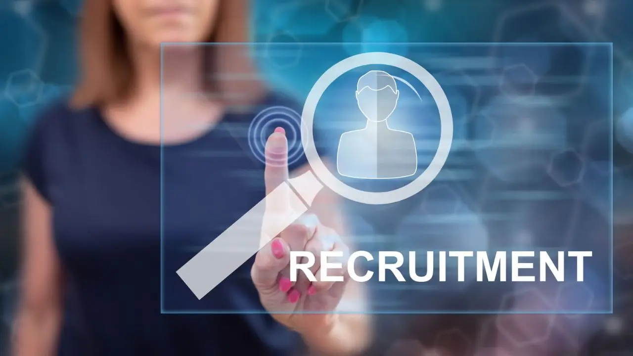 Jak napisać ogłoszenie o pracę - kobieta wskazujaca palcem na lupę i napis recruitment