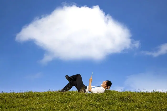 Praca mobilna w Warszawie - mężczyzna w garniturze leżu na trawie pod gołym niebem