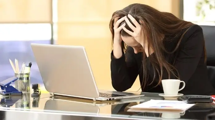 Sprostowanie świadectwa pracy - kobieta trzymająca się za głowę przed monitorem komputera