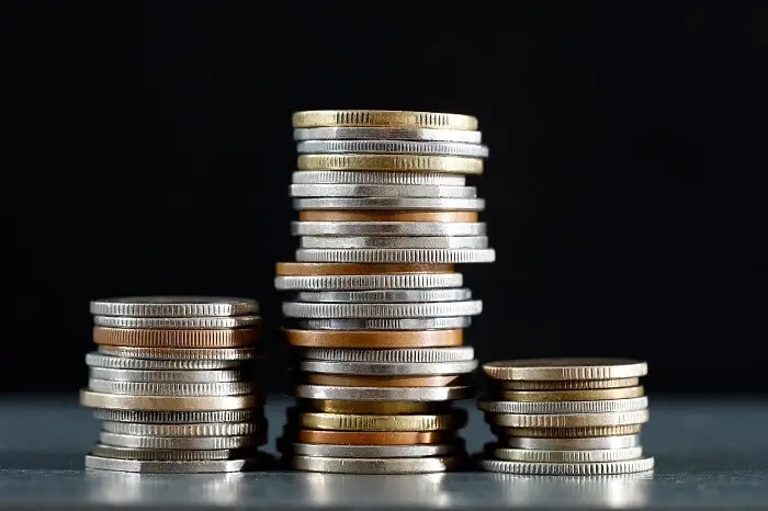 Success fee - trzy stosy monet ułożone na stole na czarnym tle