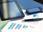 Buyer - tablet, długopis, telefon i dokumenty ze statystykami na blacie