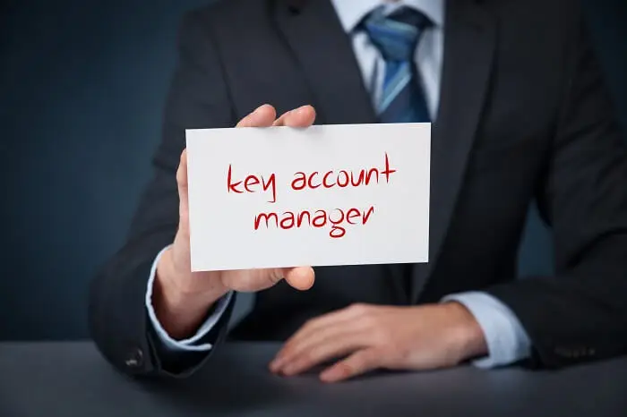 Key account manager - mężczyzna w garniturze trzymający w dłoni kartkę z napisem "key account manager"