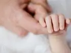 Opieka nad żoną po porodzie - męska dłoń trzymając dłoń niemowlęcia