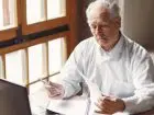 Wypłata pierwszej emerytury ZUS - emeryt przeglądający dokumenty przed komputerem