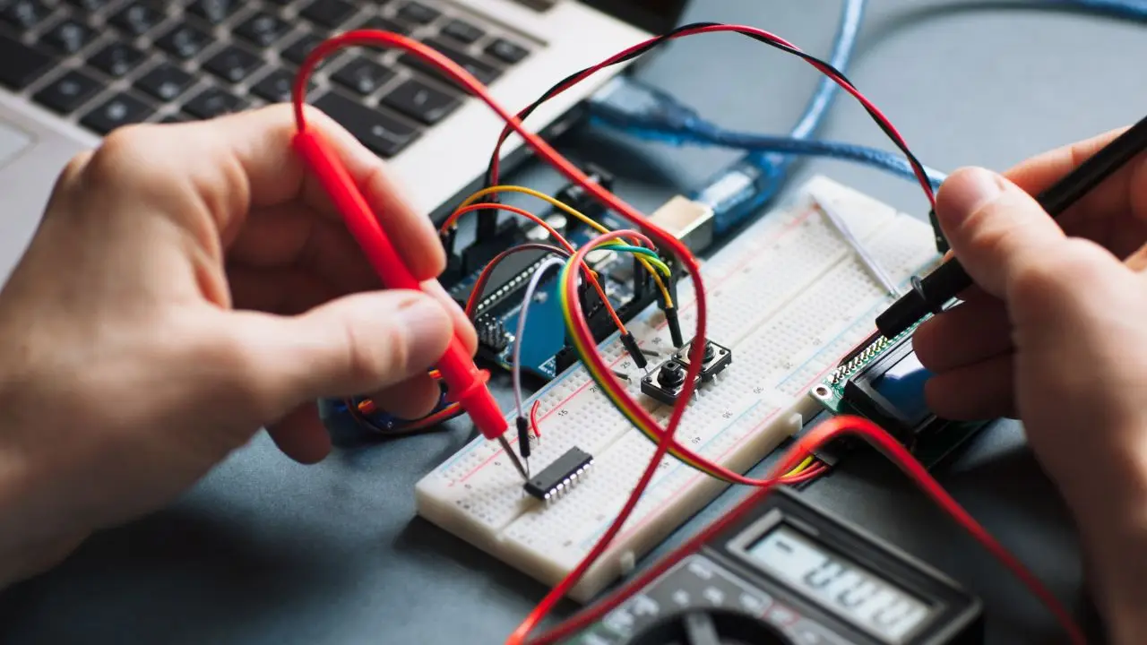 Elektronika - zbliżenie na dłonie osoby mierzącej przepływ prądu