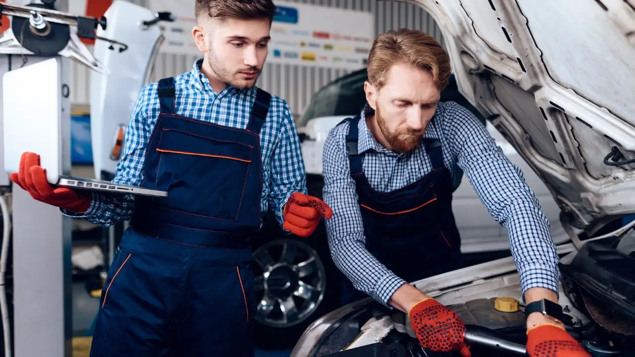 Elektryk samochodowy - mechanicy elektrycy przy samochodzie z laptopem