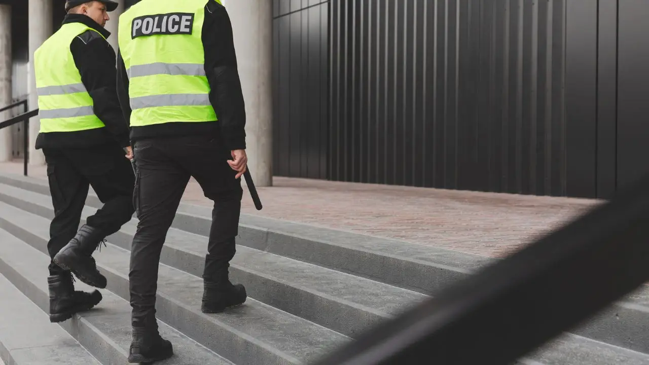 Jak zostać policjantem w UK - dwóch policjantów na służbie w kamizelkach wchodzą pod schodach
