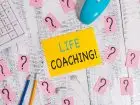 Jak zostać life coachem - karteczka z napisem "life coaching!" leżąca na biurku w otoczeniu znaków zapytania