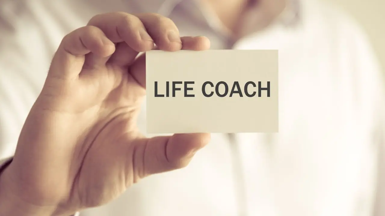 Life coach - osoba trzymająca w dłoni plakietkę z napisem life coach