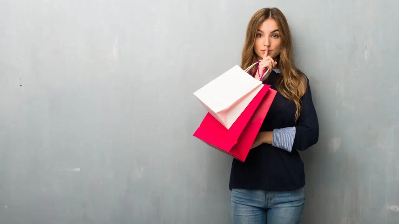 Mystery shopping - kobieta z zakupami zasłaniająca usta palcem w geście milczenia