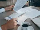 Reasekuracja - zbliżenie na dłonie osoby przeglądającej dokumenty
