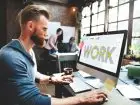 Mężczyzna pracujący przy komputerze z napisem "work" na ekranie