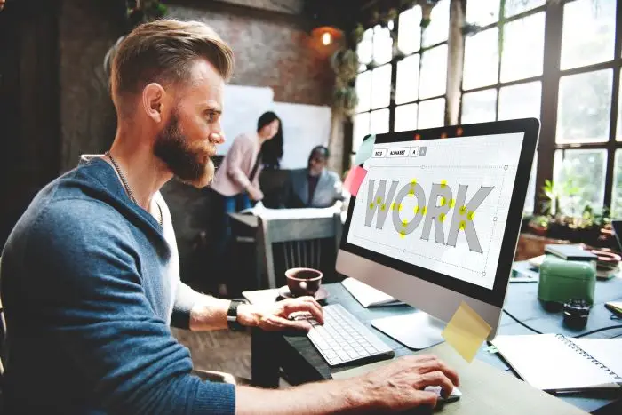 Mężczyzna pracujący przy komputerze z napisem "work" na ekranie