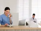 Asystent medyczny - zakres obowiązków - asystentka dzwoniąca przez telefon, na drugim planie lekarz z pacjentką