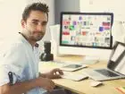 Content manager - mężczyzna pracujący przy komputerze zwrócony w stronę aparatu