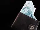 Podwyżka wynagrodzenia minimalnego w 2023 roku - portfel na czarnym tle z wystającymi pieniędzmi